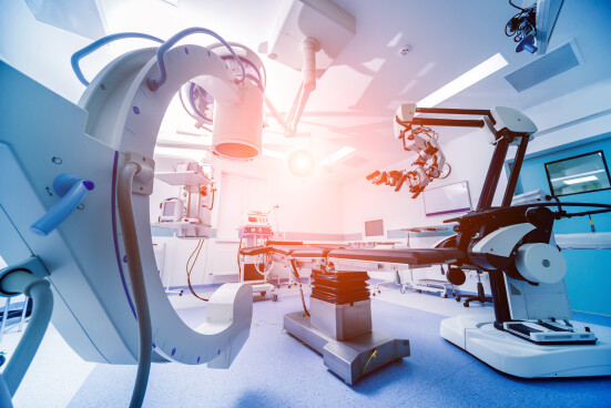 Modern equipment in operating room. Medical devices for neurosurgery. Background: Alt: "A person wearing a medical wearable device that monitors their health and sends data to their healthcare provider. In the background, a healthcare professional is using telemedicine technology to communicate with the patient and review their data, improving patient outcomes."